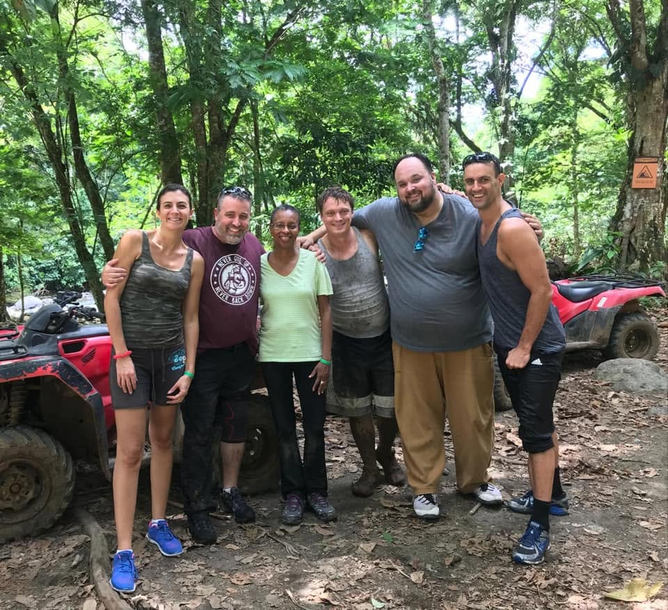 A group of muddy, smiling retreat leaders after an ATV adventure in Costa Rica