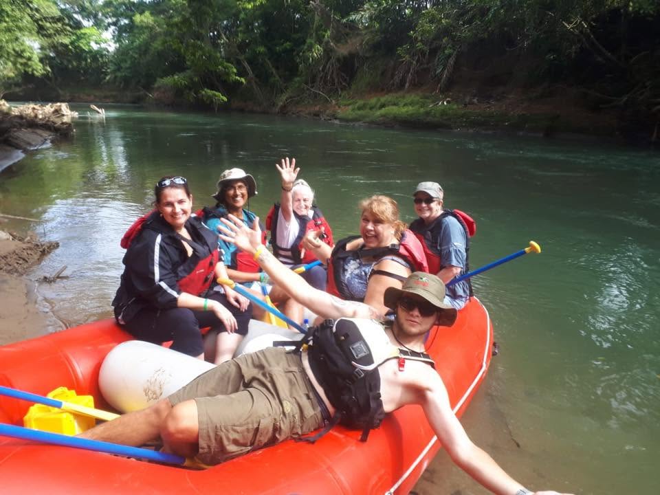 Group of retreat participants rafting together and waving from a red inflatable raft
