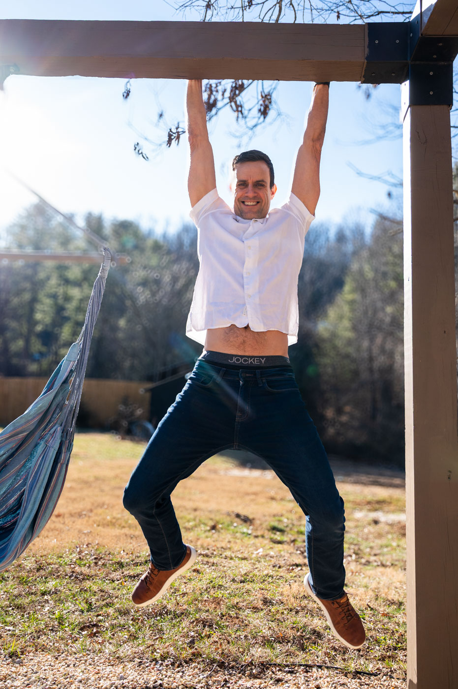 Travis Richardson hanging from a wooden beam outdoors in Asheville, North Carolina